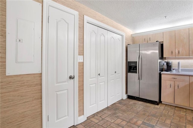 kitchen featuring light brown cabinets, electric panel, brick floor, light countertops, and stainless steel refrigerator with ice dispenser