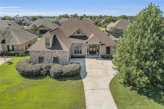 view of front of property featuring brick siding, a shingled roof, concrete driveway, a residential view, and a front lawn