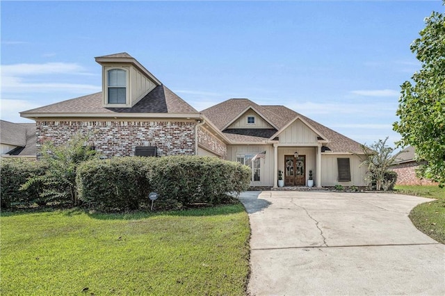 view of front of house featuring french doors, roof with shingles, brick siding, concrete driveway, and a front yard