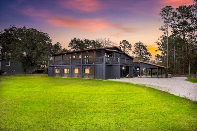 back of house at dusk with crawl space, a yard, and stairway