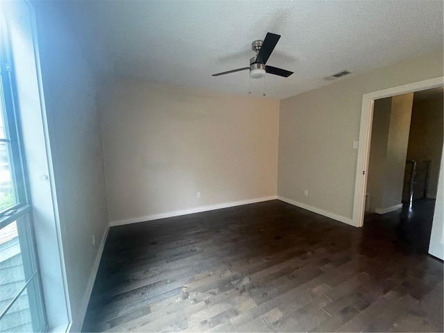 spare room with a textured ceiling, ceiling fan, and dark wood-type flooring