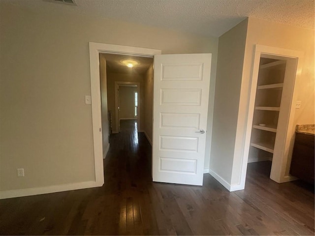 corridor featuring a textured ceiling and dark hardwood / wood-style flooring