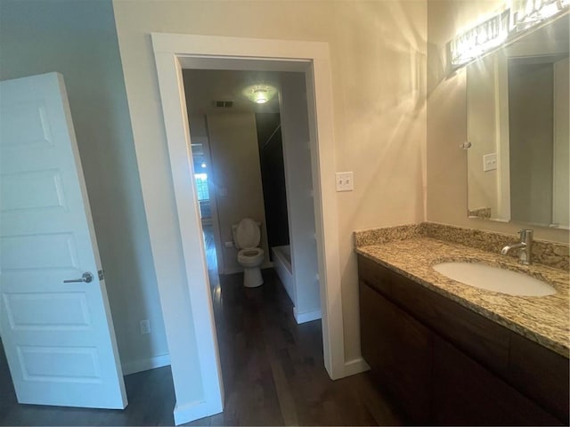 bathroom with vanity, toilet, and hardwood / wood-style flooring