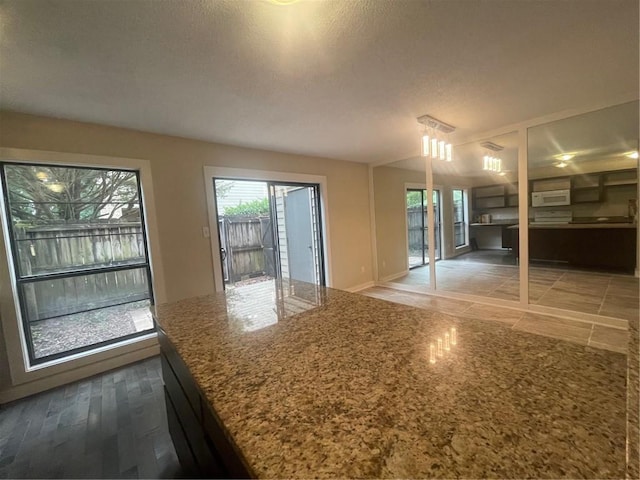 interior space featuring wood-type flooring, light stone counters, and a textured ceiling