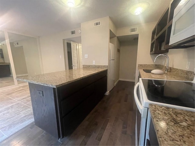 kitchen featuring white appliances, light stone countertops, dark hardwood / wood-style flooring, a textured ceiling, and sink