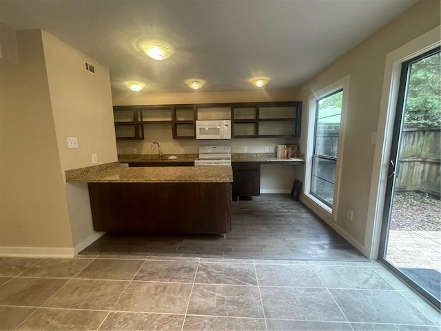 kitchen featuring built in desk, a healthy amount of sunlight, white appliances, and kitchen peninsula