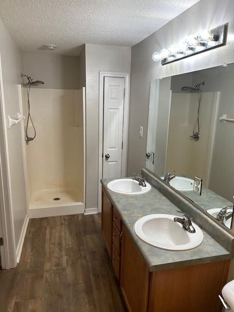 6611 Morgan Jackson Ct, Mobile, AL 36582 - bathroom with a stall shower, a textured ceiling, wood finished floors, double vanity, and baseboards