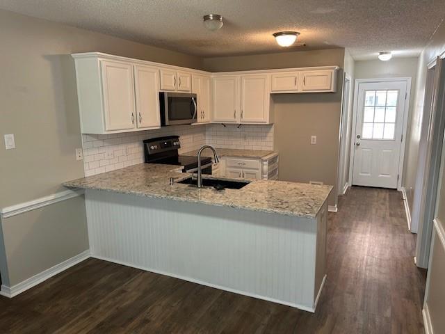 6611 Morgan Jackson Ct, Mobile, AL 36582 - kitchen with appliances with stainless steel finishes, a sink, a peninsula, white cabinetry, and a textured ceiling