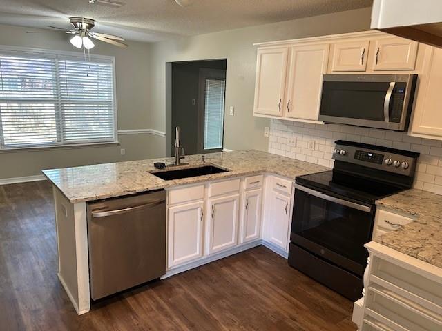 6611 Morgan Jackson Ct, Mobile, AL 36582 - kitchen featuring appliances with stainless steel finishes, a sink, a peninsula, white cabinetry, and dark wood finished floors