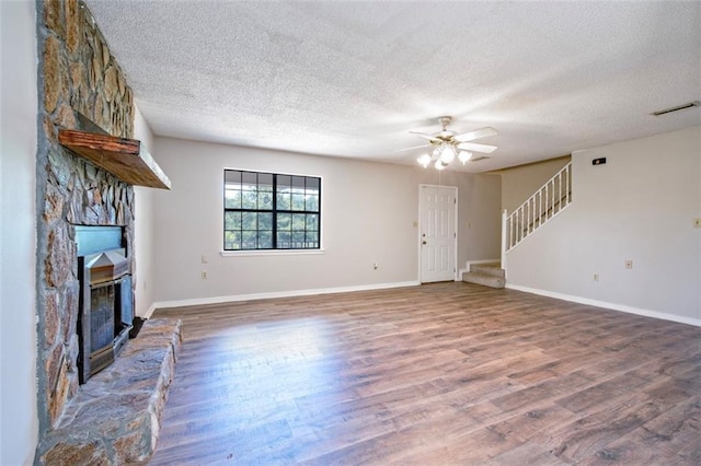 17180 Jim Platt Rd, Citronelle, AL 36522 - unfurnished living room with a textured ceiling, a stone fireplace, stairway, wood finished floors, and a ceiling fan