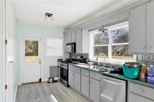 52780 State Highway 59, Stockton, AL 36579 - kitchen with decorative backsplash, light wood-type flooring, a sink, ornamental molding, and stainless steel appliances