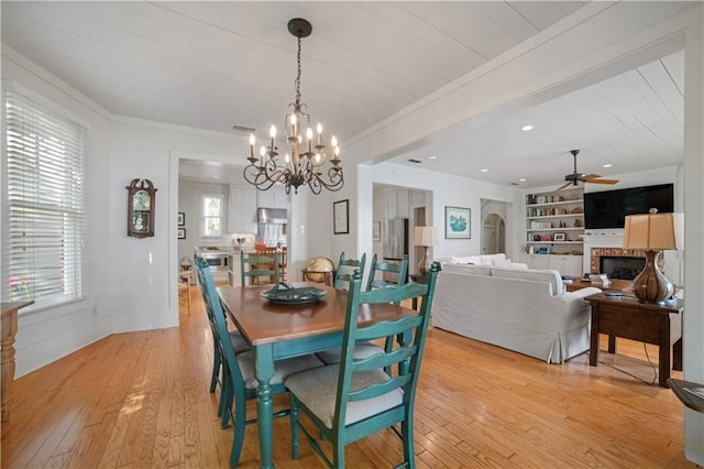 3009 Riverside Dr, Mobile, AL 36605 - dining space featuring a fireplace, light wood-type flooring, a chandelier, crown molding, and a ceiling fan