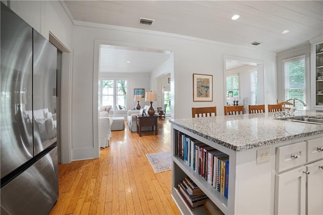 3009 Riverside Dr, Mobile, AL 36605 - kitchen with freestanding refrigerator, light wood-style flooring, white cabinetry, light stone counters, and recessed lighting