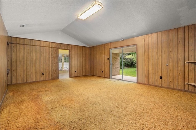 3163 Morgan Rd, Mobile, AL 36605 - spare room featuring wood walls, lofted ceiling, plenty of natural light, a textured ceiling, and carpet floors