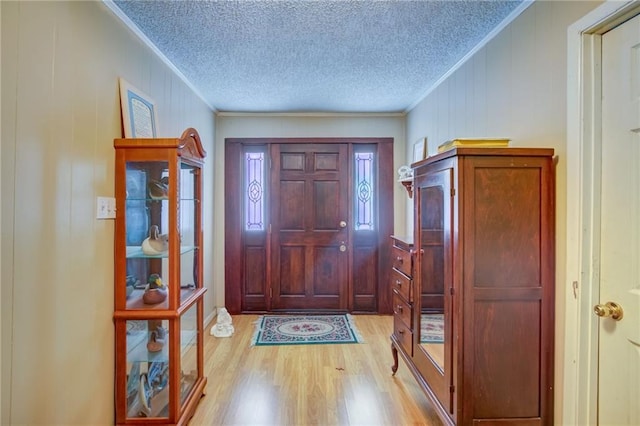 foyer featuring ornamental molding, a textured ceiling, and light hardwood / wood-style flooring