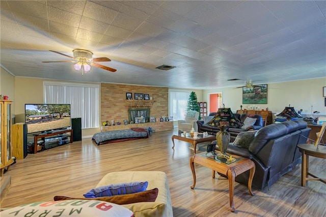 living room featuring ceiling fan, wood-type flooring, and a brick fireplace