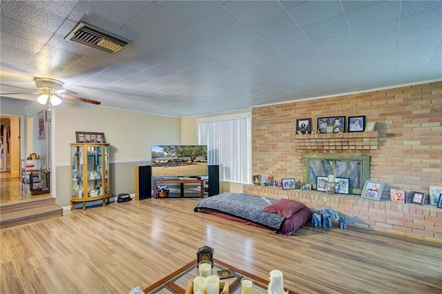 living room featuring hardwood / wood-style flooring, ceiling fan, and brick wall