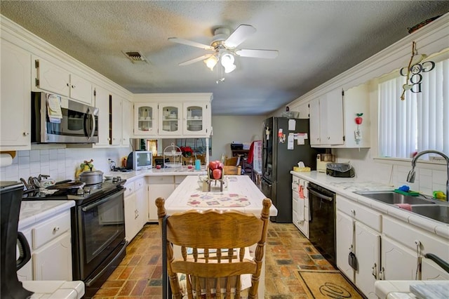 kitchen with white cabinets, backsplash, sink, and black appliances