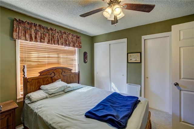 carpeted bedroom featuring two closets, ceiling fan, and a textured ceiling