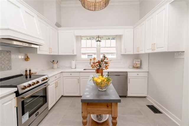 kitchen featuring stainless steel appliances, white cabinetry, premium range hood, and light tile patterned flooring