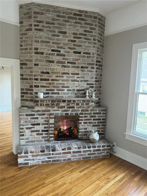 room details featuring hardwood / wood-style flooring, ornamental molding, and a brick fireplace