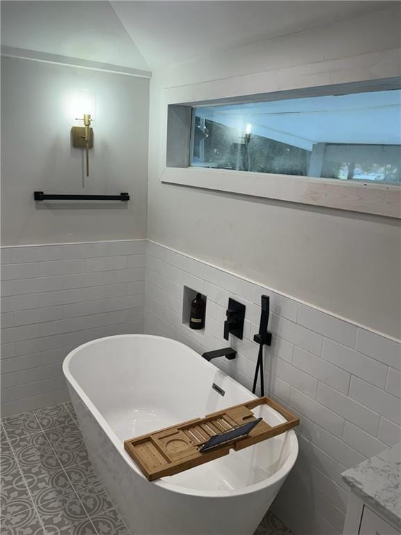 bathroom with tile walls, a washtub, and tile patterned floors