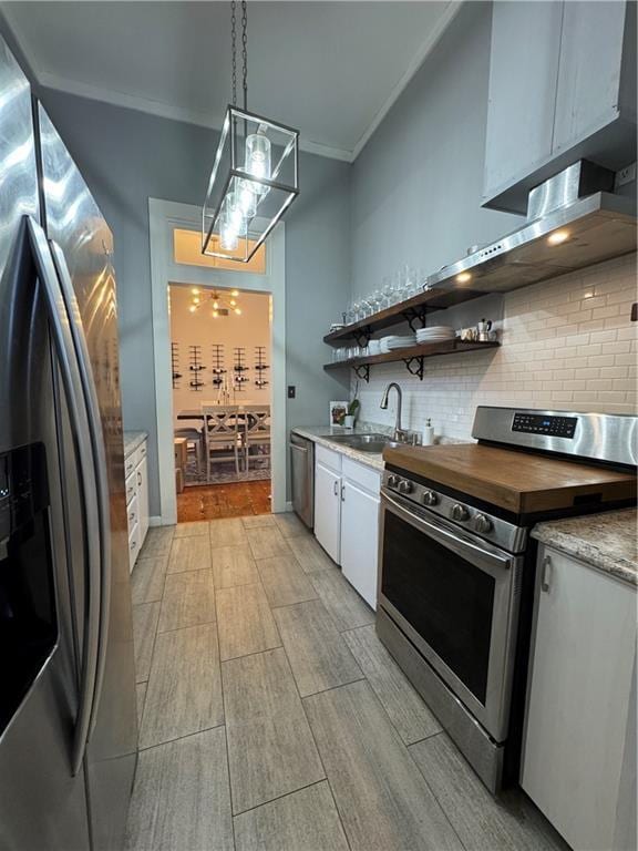 kitchen with sink, white cabinetry, decorative light fixtures, ornamental molding, and stainless steel appliances