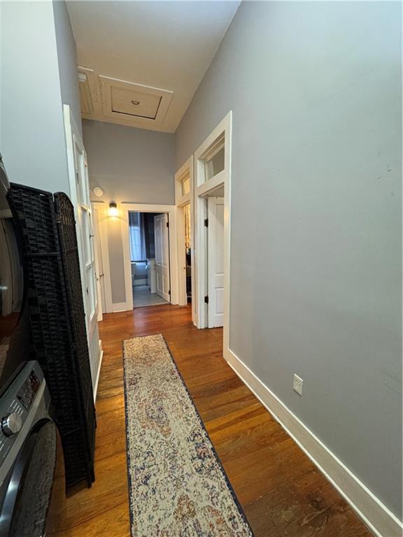 hallway with wood-type flooring and stacked washing maching and dryer