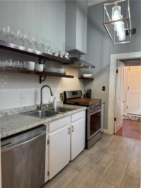 kitchen featuring appliances with stainless steel finishes, decorative light fixtures, tasteful backsplash, sink, and white cabinets