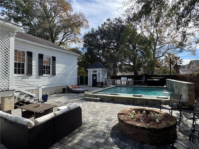 view of pool with a patio area, a shed, and an outdoor living space with a fire pit