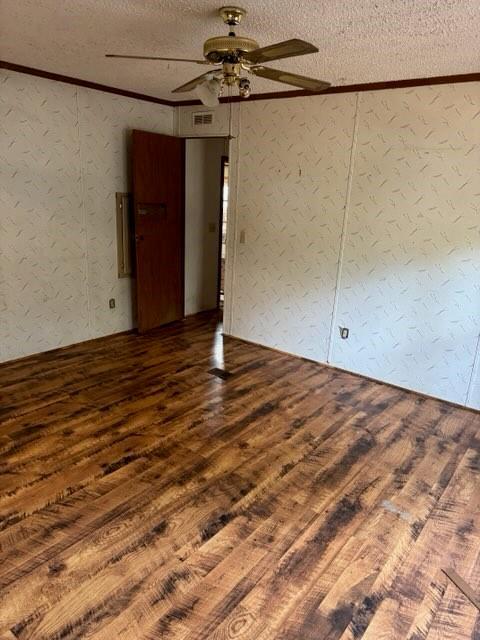 spare room featuring crown molding, ceiling fan, wood-type flooring, and a textured ceiling