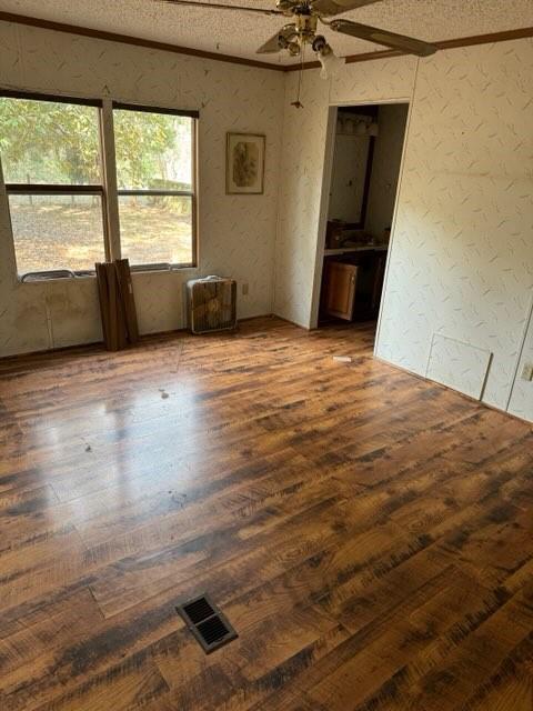 unfurnished room featuring ceiling fan, ornamental molding, dark hardwood / wood-style flooring, and a textured ceiling