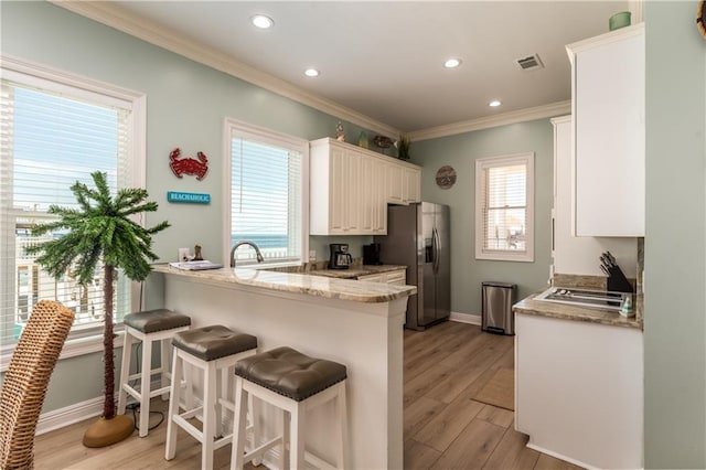106 Serigny Ct, Dauphin Island, AL 36528 - kitchen with stainless steel fridge with ice dispenser, ornamental molding, a peninsula, baseboards, and a kitchen bar