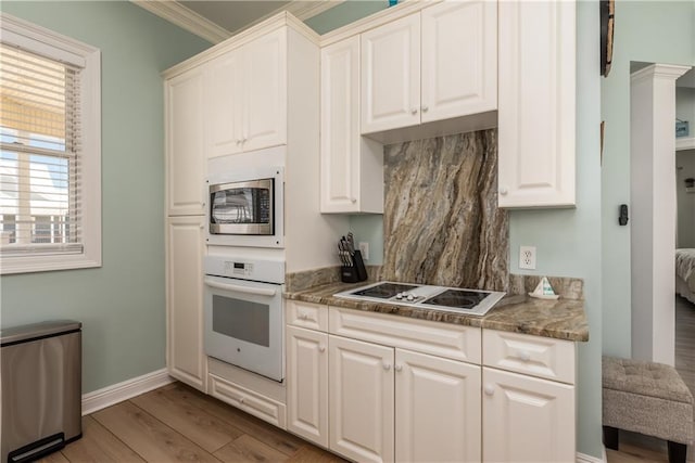 106 Serigny Ct, Dauphin Island, AL 36528 - kitchen featuring white appliances, light wood-type flooring, baseboards, white cabinetry, and crown molding