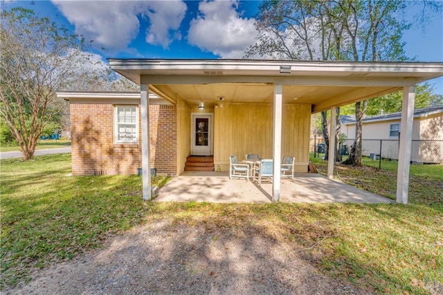 property entrance featuring a yard, brick siding, a patio area, and fence