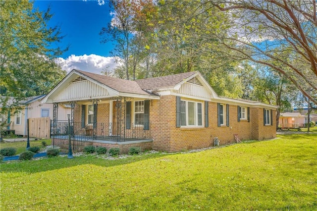 exterior space featuring brick siding, covered porch, and a front yard