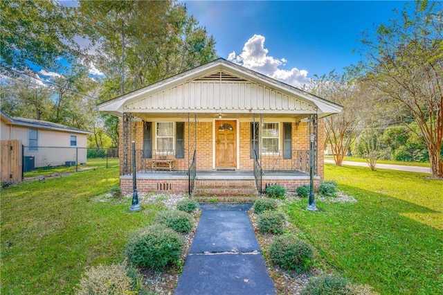 bungalow-style house featuring brick siding, a porch, fence, and a front yard