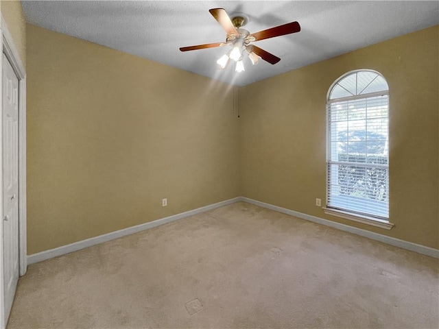 carpeted empty room with ceiling fan and a textured ceiling