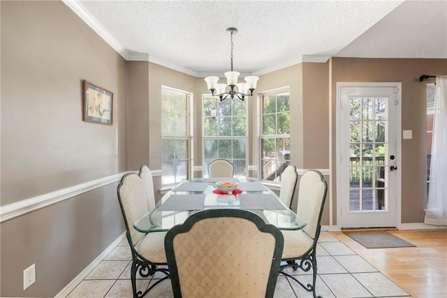 dining space featuring a textured ceiling, light hardwood / wood-style floors, an inviting chandelier, and crown molding