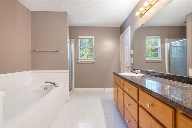 bathroom with plus walk in shower, a textured ceiling, vanity, and a wealth of natural light