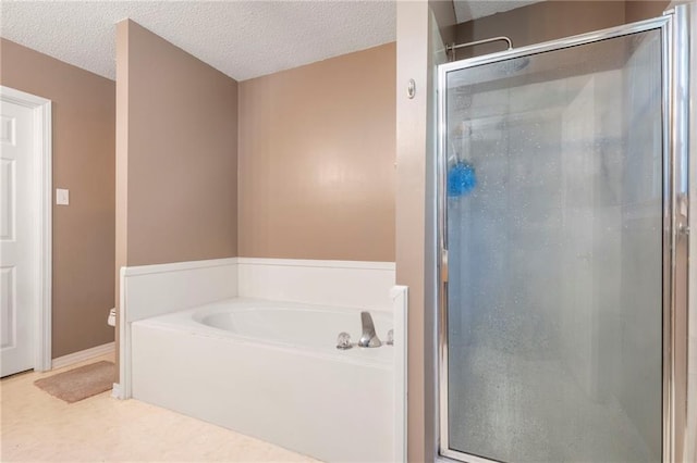 bathroom with a textured ceiling and shower with separate bathtub