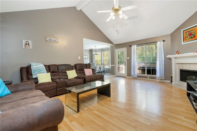 living room featuring beamed ceiling, ceiling fan with notable chandelier, light hardwood / wood-style flooring, and a tile fireplace