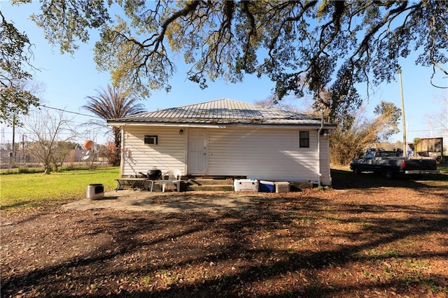 back of property with metal roof and a lawn