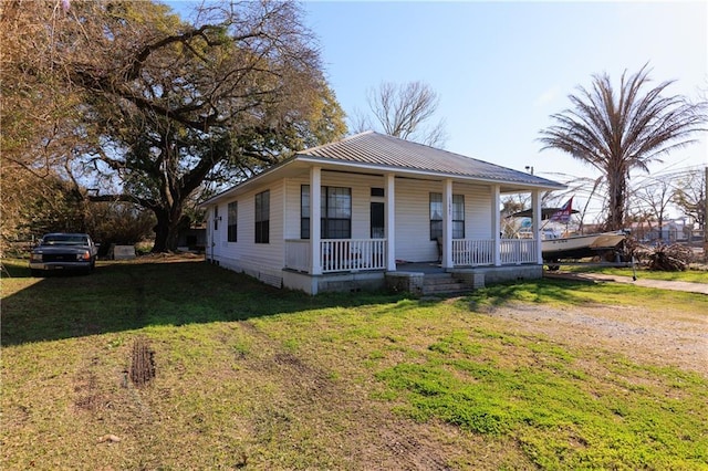 view of front facade featuring a front yard, covered porch, and metal roof