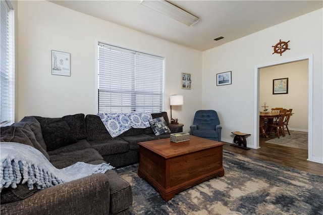 living room featuring visible vents, baseboards, and wood finished floors