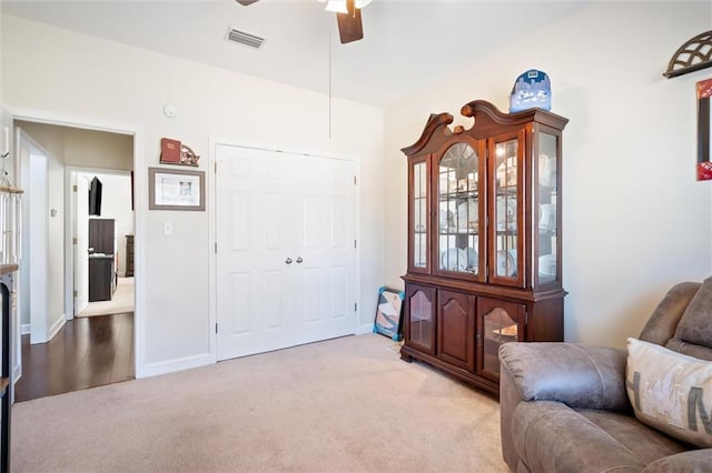 living area featuring ceiling fan and light colored carpet