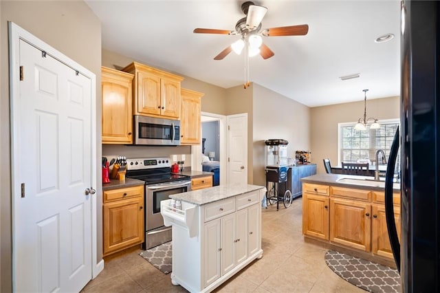 kitchen featuring stainless steel appliances, a center island, light tile flooring, decorative light fixtures, and ceiling fan with notable chandelier