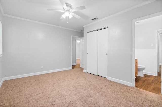 unfurnished bedroom with ceiling fan, carpet flooring, connected bathroom, a closet, and crown molding