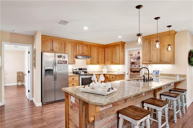 kitchen with sink, hanging light fixtures, hardwood / wood-style flooring, kitchen peninsula, and stainless steel appliances