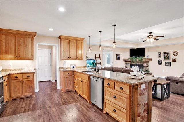 kitchen featuring dishwasher, sink, ceiling fan, a fireplace, and decorative light fixtures